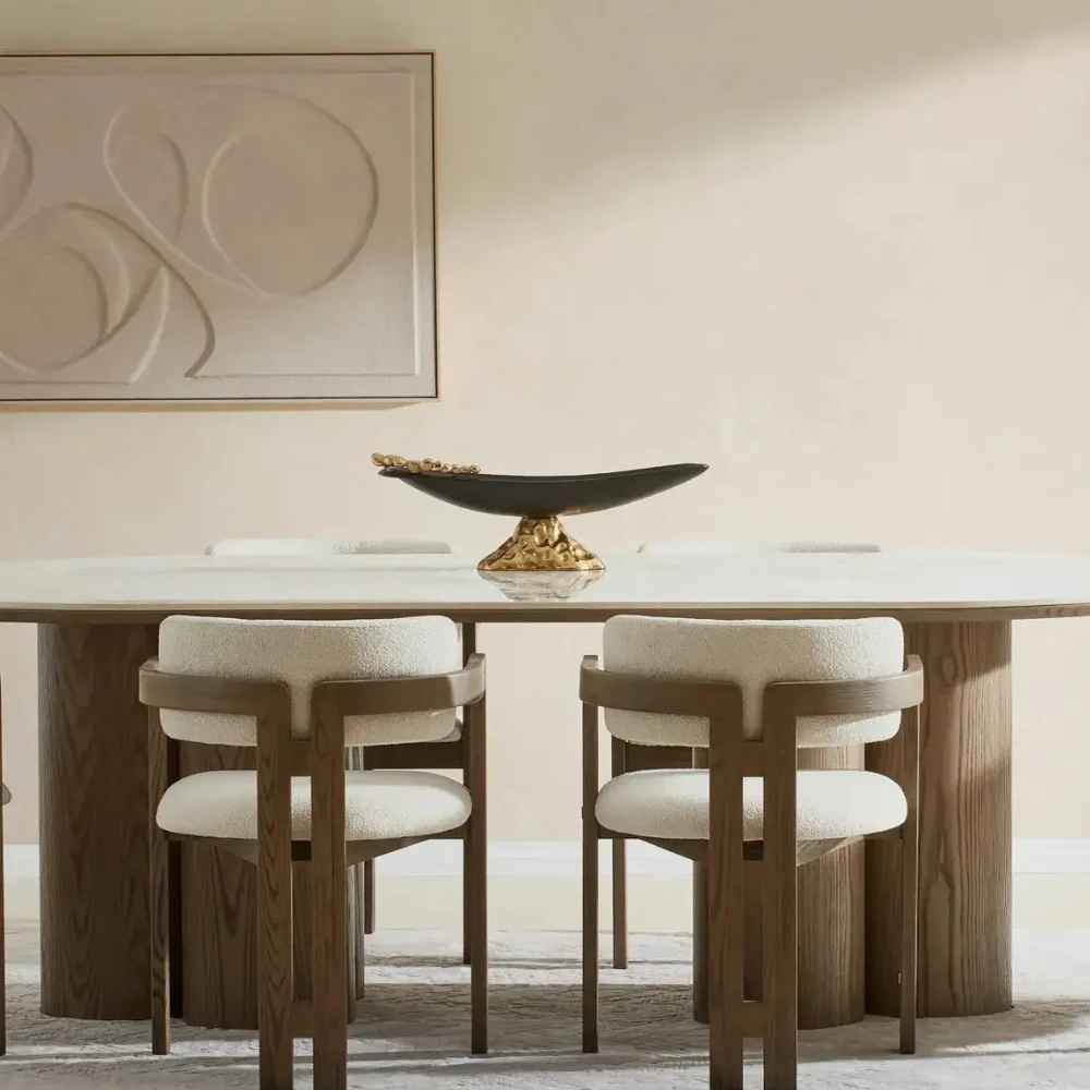 Oval Dining Table with a white sintered stone table top, supported by three cylindrical medium-brown wooden columns on each side. Seats up to 8 people.